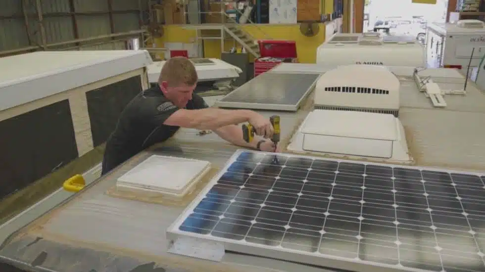 Technician installing solar panels on van for off-grid adventures