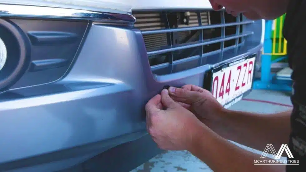 Upgrading car safety: Technician installs parking sensor system for better rear awareness