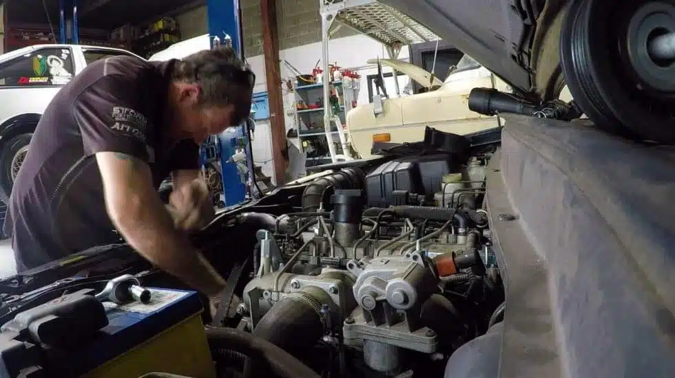 Mechanic diagnoses car engine issue under the open hood