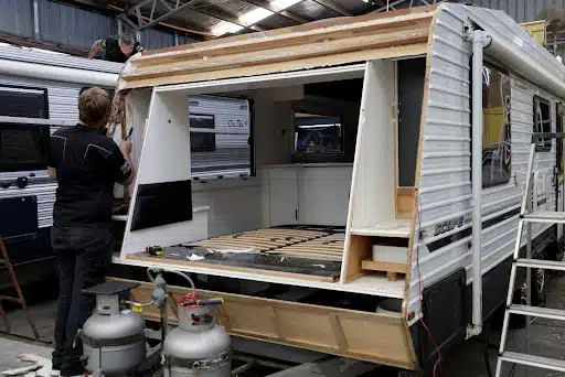 Extensive caravan repairs underway: Technician works on the exposed interior in a workshop