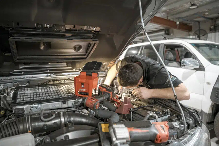 Technician diagnoses and fixes car problems under the hood or underneath the car