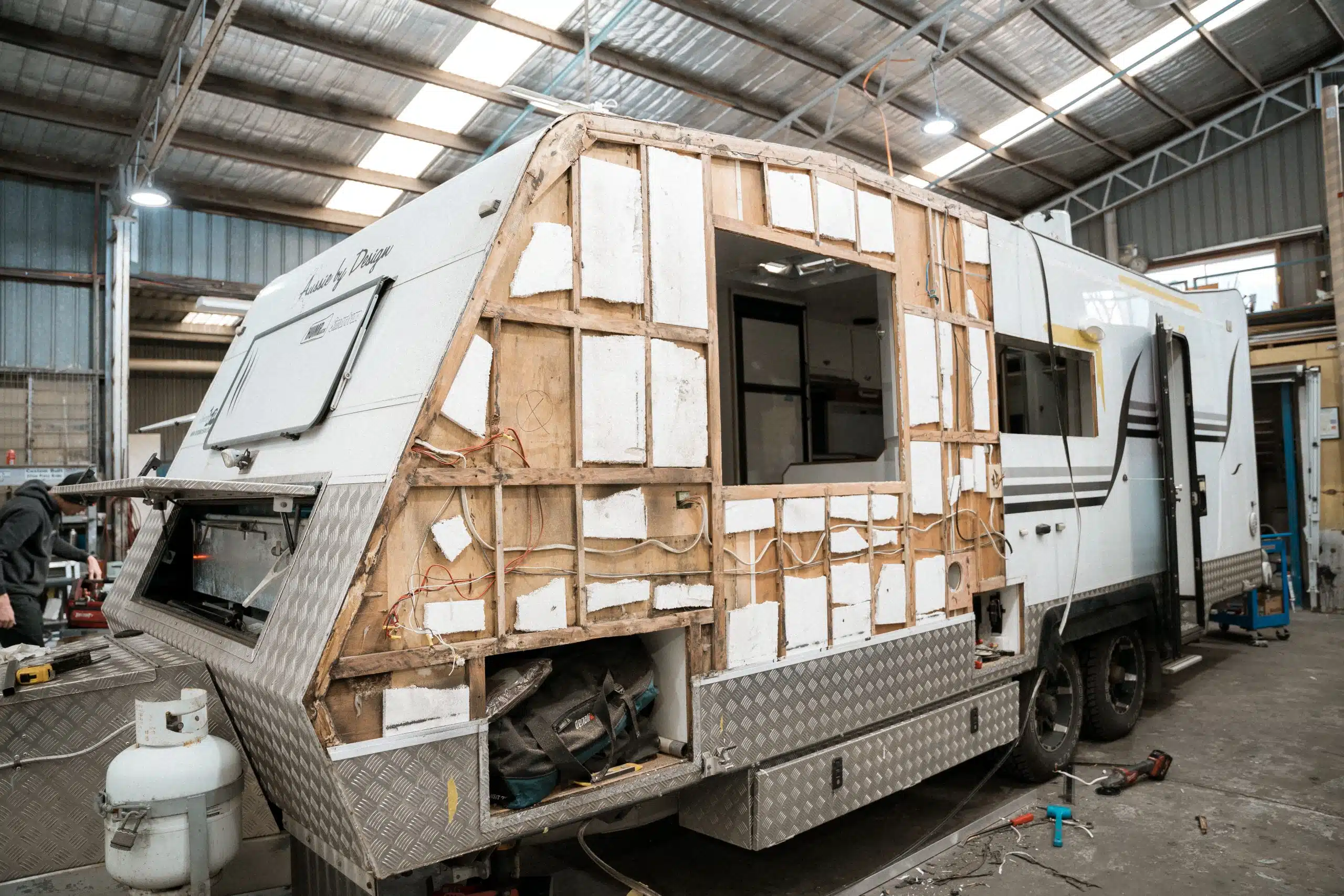 Technician installs additional storage compartments on a caravan sidewall